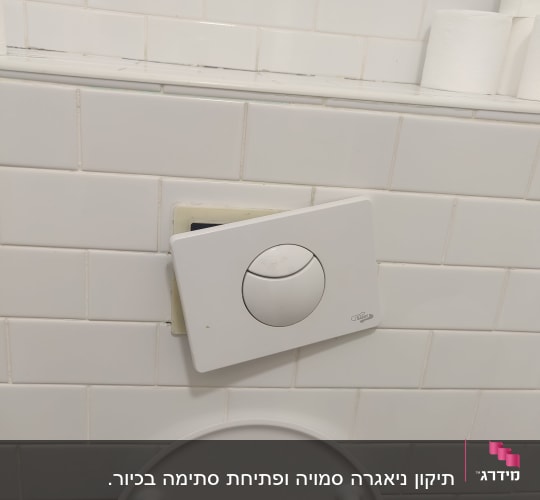 לחצן הדחה שבור על קיר אריחים לבנים